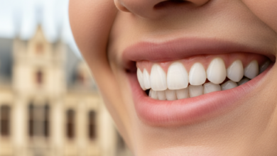 Close-up of a bright, healthy smile with perfectly contoured pink gums and sparkling white teeth, set against a softly blurred, neutral background suggesting a European city street in Belgium.