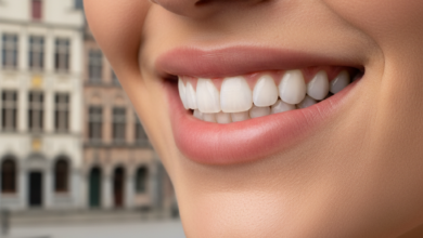Close-up of a bright, healthy smile featuring perfectly aligned, natural-looking teeth. The background is softly blurred, subtly hinting at a Belgian architectural scene, representing successful dental veneer procedures.