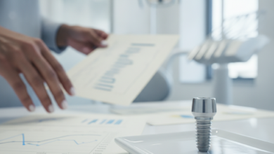 A close-up, photorealistic view inside a modern dental clinic. A stylized model of a dental implant sits on a sterile surface in the foreground. In the soft-focus background, hands are seen reviewing abstract, blurred financial documents, representing the intersection of dental care and insurance costs.