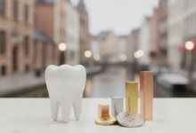 A stylized white tooth model on a clean surface, next to abstract, non-identifiable shapes suggesting varying financial costs. The background is a very blurred image of Ghent's historic cityscape, with hints of medieval buildings and canals. The lighting is soft and cinematic, with a shallow depth of field.